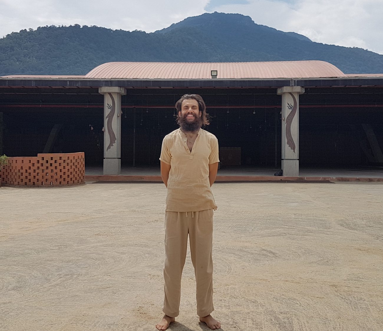 Sid barefoot in the courtyard of an ashram, mountains behind